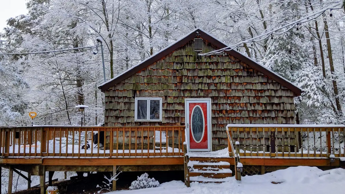 The cabin's red door framed by fresh deep snow on the deck rails